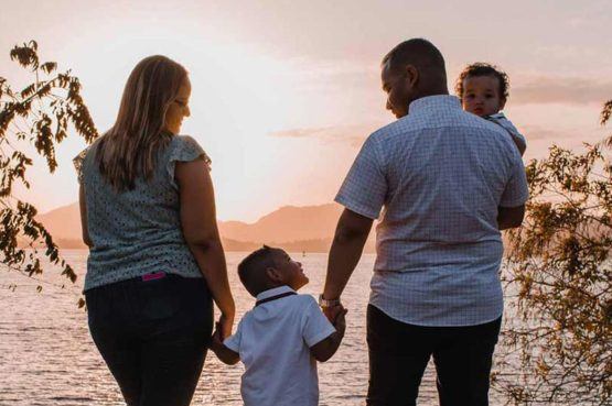 a family with two young boys smiling hand in hand overlooking the sunset